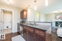 Kitchen featuring wood-finish flooring, dark wood cabinetry, granite countertops, and stainless steel appliances - 