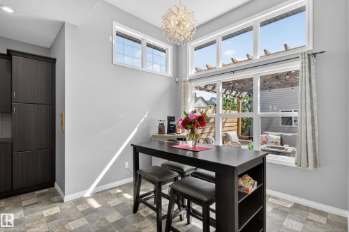 Dining area featuring a modern chandelier, large windows, and dark wood-finish cabinetry - 9847 220 Street Nw, Edmonton, AB - Indoor Photo Showing Dining Room