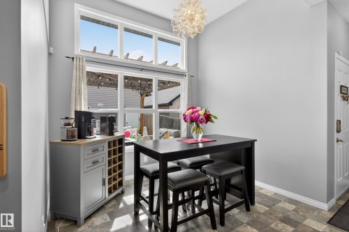 Dining area featuring a contemporary chandelier, a high-top dining table with four stools, and a built-in cabinetry unit - 9847 220 Street Nw, Edmonton, AB - Indoor
