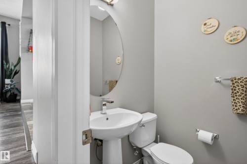 Pedestal sink with a modern faucet and an oval mirror, complemented by an adjacent toilet - 9847 220 Street Nw, Edmonton, AB - Indoor Photo Showing Bathroom