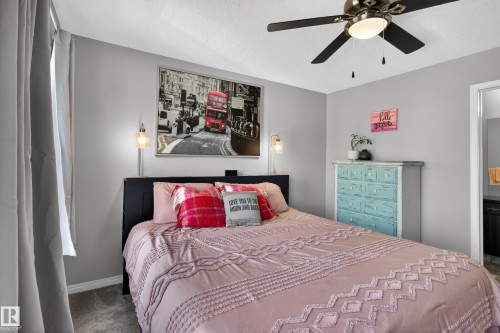 Carpeted room featuring a ceiling fan with integrated lighting, wall-mounted sconces, and a doorway opening to an additional space - 9847 220 Street Nw, Edmonton, AB - Indoor Photo Showing Bedroom