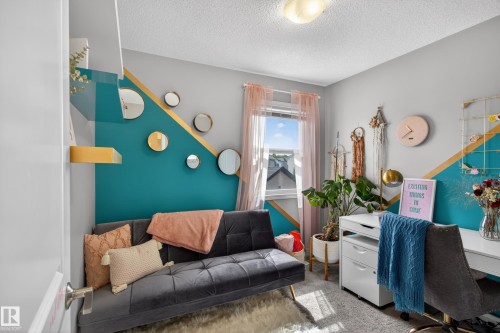 Room featuring a window, wall-mounted shelving, and a decorative accent wall with geometric teal and gold detailing - 9847 220 Street Nw, Edmonton, AB - Indoor