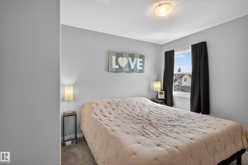 Bedroom featuring light gray wall paint, a window with black privacy curtains, and textured ceiling finish - 9847 220 Street Nw, Edmonton, AB - Indoor Photo Showing Bedroom