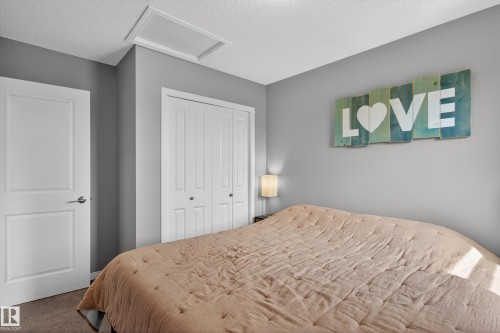 Room featuring soft gray walls, a textured ceiling, a white paneled door, and bi-fold closet doors - 9847 220 Street Nw, Edmonton, AB - Indoor Photo Showing Bedroom