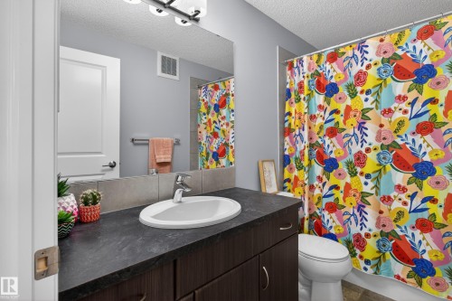Bathroom vanity featuring a dark countertop with an undermount sink and a polished chrome faucet - 9847 220 Street Nw, Edmonton, AB - Indoor Photo Showing Bathroom