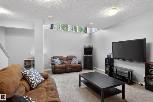 Spacious recreation room featuring light gray walls and plush carpeting - 9847 220 Street Nw, Edmonton, AB - Indoor Photo Showing Living Room