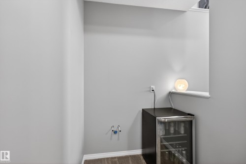Recessed alcove with light gray walls and carpet flooring, featuring a built-in electrical outlet and water line connections - 9847 220 Street Nw, Edmonton, AB - Indoor