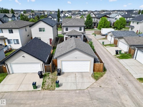 Rear-facing two-story residence featuring light siding and a dark shingle roof, accompanied by a detached single-car garage with a white panel door - 9847 220 Street Nw, Edmonton, AB - Outdoor
