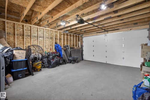 Spacious garage featuring a concrete floor, exposed wood ceiling joists, and an automatic garage door opener - 9847 220 Street Nw, Edmonton, AB - Indoor Photo Showing Garage