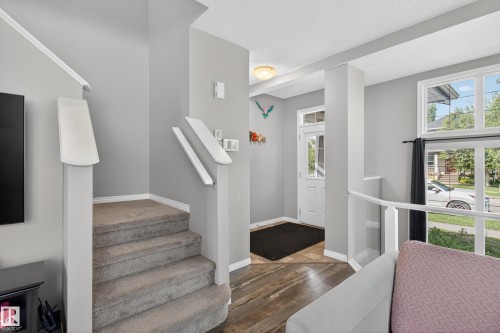 Entry foyer featuring wood-finish flooring, a white paneled entry door with transom window, and an adjacent multi-pane window - 9847 220 Street Nw, Edmonton, AB - Indoor Photo Showing Other Room
