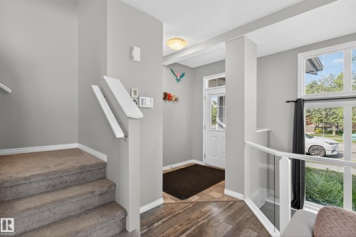 Foyer entry with wood-finish flooring, a carpeted staircase, and a glass-paneled railing - 9847 220 Street Nw, Edmonton, AB - Indoor Photo Showing Other Room