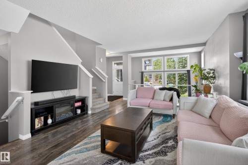 Open concept living area featuring wood-finish flooring, light gray wall paint, and a white trim package - 9847 220 Street Nw, Edmonton, AB - Indoor Photo Showing Living Room