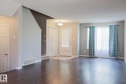 Spacious living area featuring wood-finish flooring, ample natural light from large windows, and a neutral color palette - 