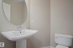 Pedestal sink with chrome faucet, complemented by an oval wall mirror and a white toilet - 
