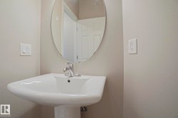 Pedestal sink with chrome faucet and an oval wall-mounted mirror - 