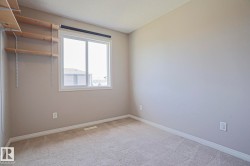 Carpeted room featuring a white-framed window, neutral painted walls, and built-in adjustable shelving - 