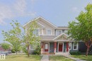 Two-story duplex featuring complementary siding, red entry doors, and white trim accents - 489 Orchards Boulevard Sw, Edmonton, AB  - Outdoor With Facade 