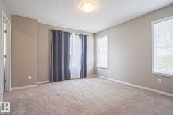 Spacious room featuring neutral paint tones, multiple windows with blinds, and light-colored carpet flooring - 