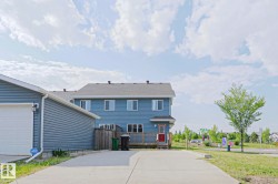 Rear exterior featuring a red entry door, private deck, and blue siding - 