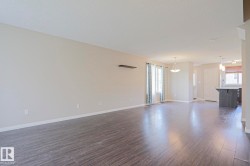 Spacious open-concept living area featuring wood-finish flooring, neutral wall tones, and recessed lighting - 