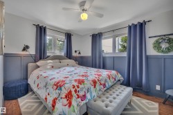Bedroom featuring wood-finish flooring, two windows, and board and batten wall detailing - 