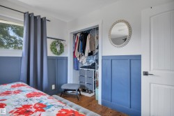 Bedroom featuring a closet with bi-fold door potential, wood-finish flooring, and white board and batten wall paneling - 