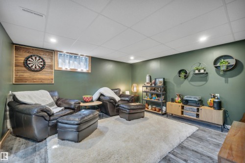 Spacious room featuring wood-finish flooring, a drop ceiling with recessed lighting, and a window with integrated lighting - 5302 52 Ave, Wetaskiwin, AB - Indoor Photo Showing Basement