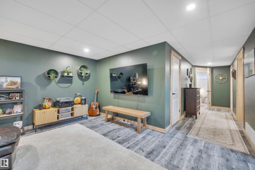 Recreation room featuring recessed lighting, paneled ceiling, wood-finish flooring, and a wall-mounted television - 5302 52 Ave, Wetaskiwin, AB - Indoor Photo Showing Other Room