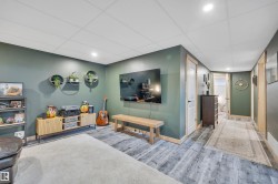 Recreation room featuring recessed lighting, paneled ceiling, wood-finish flooring, and a wall-mounted television - 