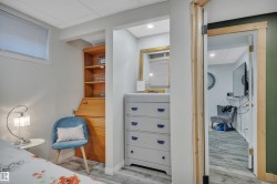 Lower-level room featuring light gray walls, a window with blinds, and wood-finish flooring - 