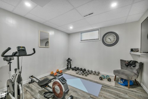 Spacious room featuring wood-finish flooring, light grey paneled walls, recessed lighting, and a drop ceiling - 5302 52 Ave, Wetaskiwin, AB - Indoor Photo Showing Gym Room