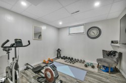 Spacious room featuring wood-finish flooring, light grey paneled walls, recessed lighting, and a drop ceiling - 