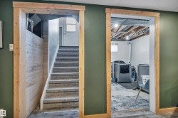 Stairwell with carpeted treads and natural wood trim, complemented by a laundry area featuring exposed ceiling joists and concrete flooring - 