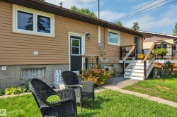 Exterior featuring tan siding, a ground-level window with a white frame, and a concrete block foundation - 