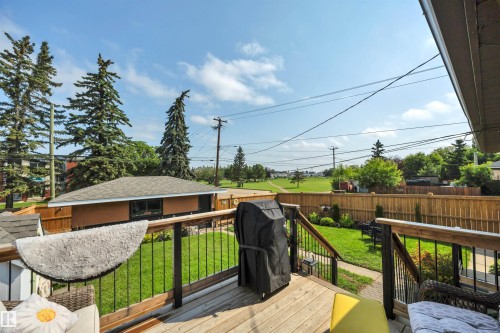Hardwood-finish deck with black metal spindle railings and a slatted wood privacy fence enclosing a grass lawn - 5302 52 Ave, Wetaskiwin, AB - Outdoor With Deck Patio Veranda