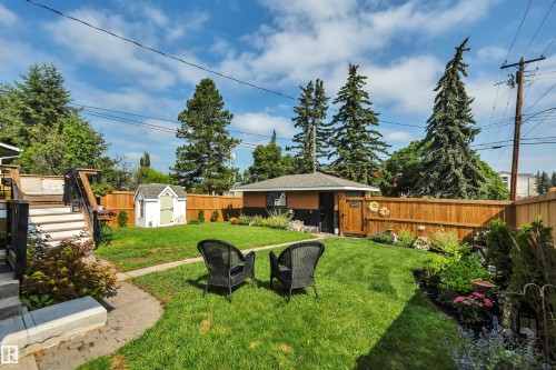 Expansive backyard featuring a manicured lawn, tiered wood deck with stairs, a detached shed, a separate outbuilding with a shingled roof, and a wood fence - 5302 52 Ave, Wetaskiwin, AB - Outdoor With Deck Patio Veranda