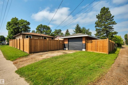Detached garage with a dark sectional door, brick accents, and a shingled roof - 5302 52 Ave, Wetaskiwin, AB - Outdoor