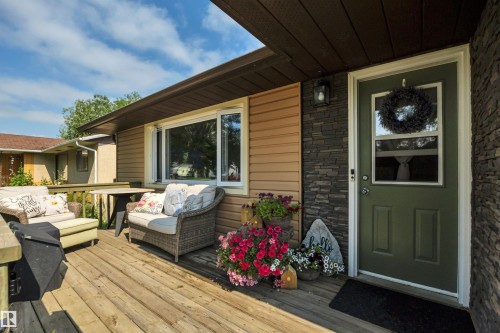 Expansive wooden deck featuring horizontal siding, a dark stone veneer accent wall, and a dark green entry door with an upper window - 5302 52 Ave, Wetaskiwin, AB - Outdoor With Deck Patio Veranda With Exterior
