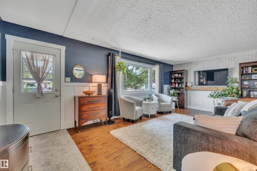 Bright living area with wood-finish flooring and a large window - 5302 52 Ave, Wetaskiwin, AB - Indoor Photo Showing Living Room