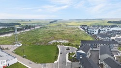Expansive undeveloped land parcel framed by agricultural fields and emerging residential developments - 
