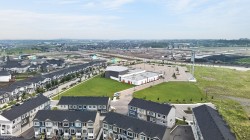Aerial perspective showcasing a developing residential area with modern townhomes featuring dark roofs and varied siding - 