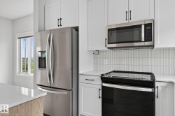 Modern kitchen featuring white cabinetry, stainless steel appliances, a white picket tile backsplash, and light countertops - 