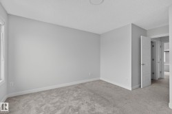 Neutral-toned room featuring a light gray wall color, white trim, and gray carpet flooring - 