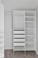 Customizable closet system featuring white shelving, multiple hanging rods, four integrated drawers, and a lower wire basket - 