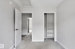 Carpeted room featuring a built-in closet with shelving, white trim, and a white panel door with black hardware - 