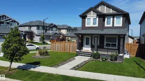 Two-story residence featuring a dark facade with stone accents and a covered front porch - 17359 49 Street Nw, Edmonton, AB - Outdoor With Deck Patio Veranda With Facade