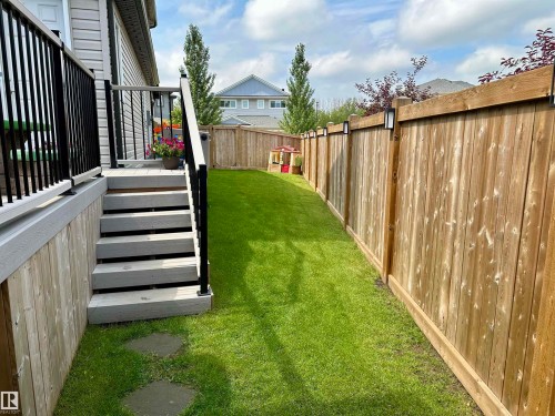 Expansive grassy backyard featuring a full privacy fence with integrated wall sconces - 17359 49 Street Nw, Edmonton, AB - Outdoor
