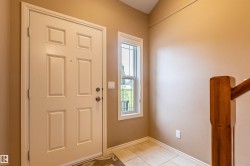 Entryway featuring a four-panel door, an adjacent sidelight window, and tile flooring - 
