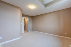 Spacious interior featuring neutral carpeting, light beige wall paint, white trim, and a tray ceiling with a flush-mount light fixture - 