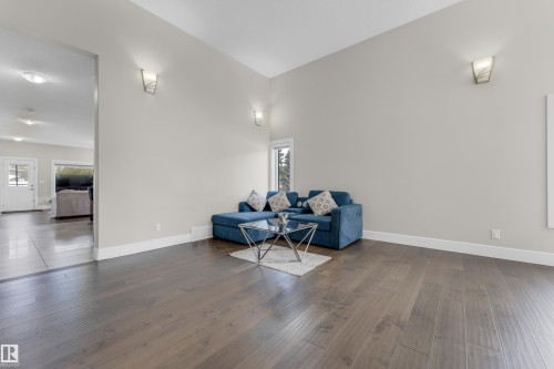 Spacious living area featuring wide plank wood-finish flooring, high ceilings, and recessed wall sconces - 4506 49 Avenue, Beaumont, AB - Indoor